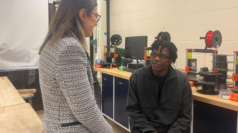 A student and a teacher talk together in a lab.